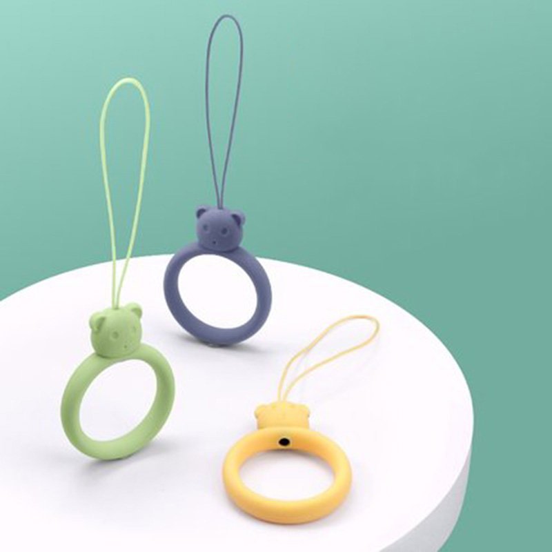 Um cordão de silicone para um anel de urso de telefone em um dedo verde