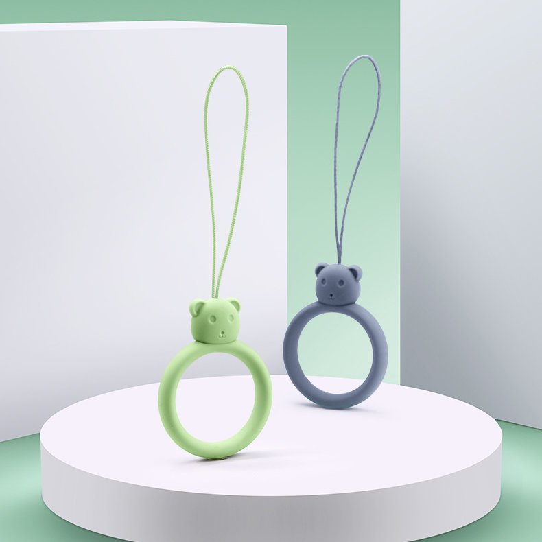 Um cordão de silicone para um anel de urso de telefone em um dedo verde